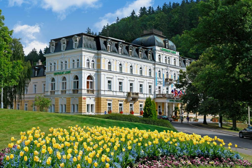 un gran edificio blanco con flores delante en Ensana Centrální Lázně - Maria Spa, en Mariánské Lázně