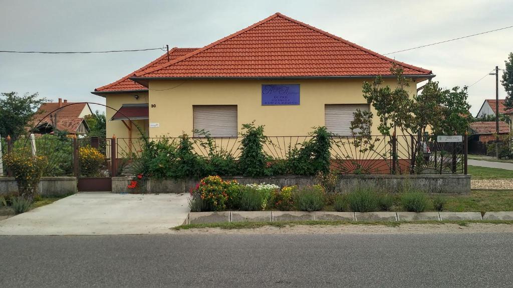 une maison jaune avec un toit rouge dans l'établissement Abigél Apartman, à Mórahalom