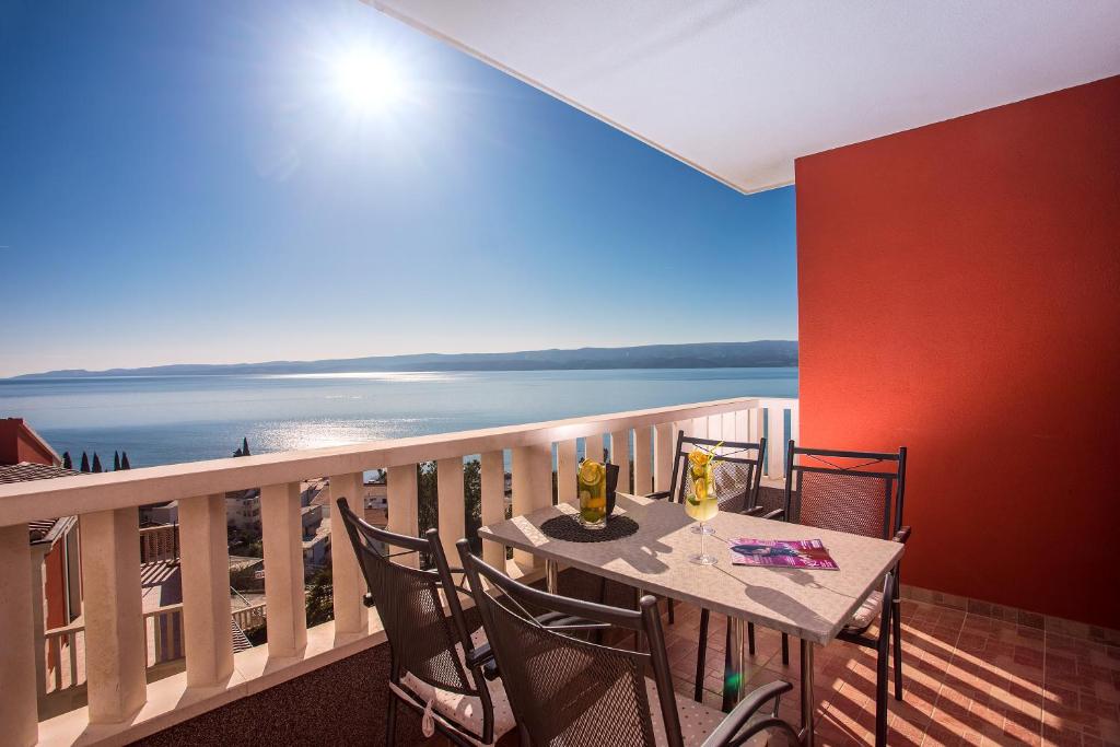 a balcony with a table and chairs with a view of the ocean at Apartments Bakota in Omiš