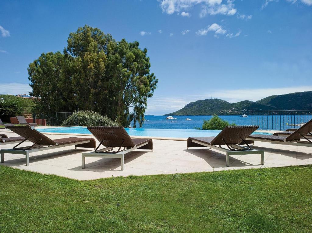 una fila di sedie a sdraio accanto alla piscina di Hotel Shegara a Porto Vecchio