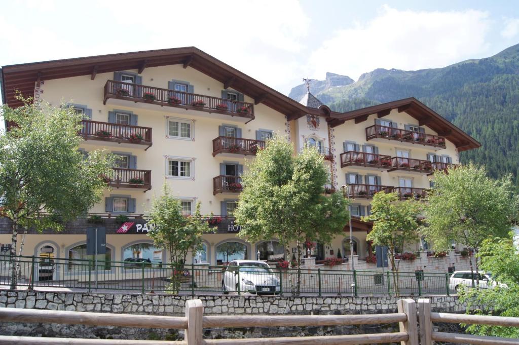 un grande edificio con macchine parcheggiate di fronte di Albergo Alla Rosa a Canazei