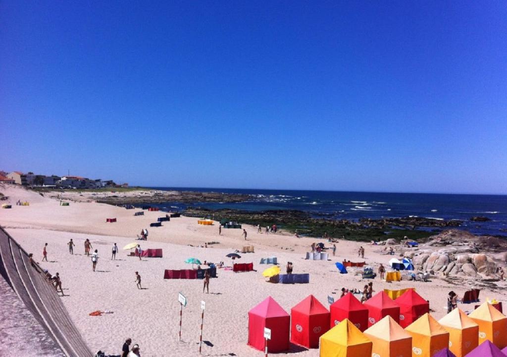 un groupe de personnes sur une plage avec l'océan dans l'établissement Trajadinha FêloHouse, à Caminha