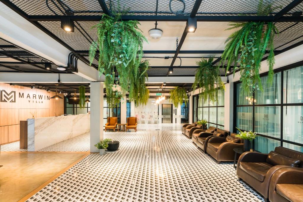 a large lobby with leather chairs and plants at Marwin Villa in Bangkok