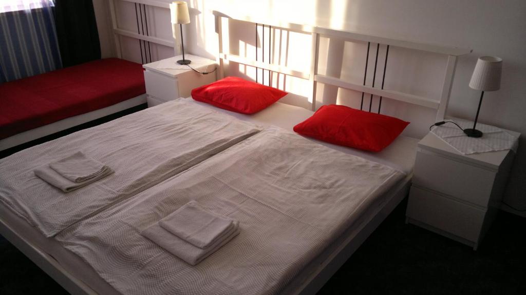 1 dormitorio con cama blanca y almohadas rojas en Apartment Maximilian, en Bratislava