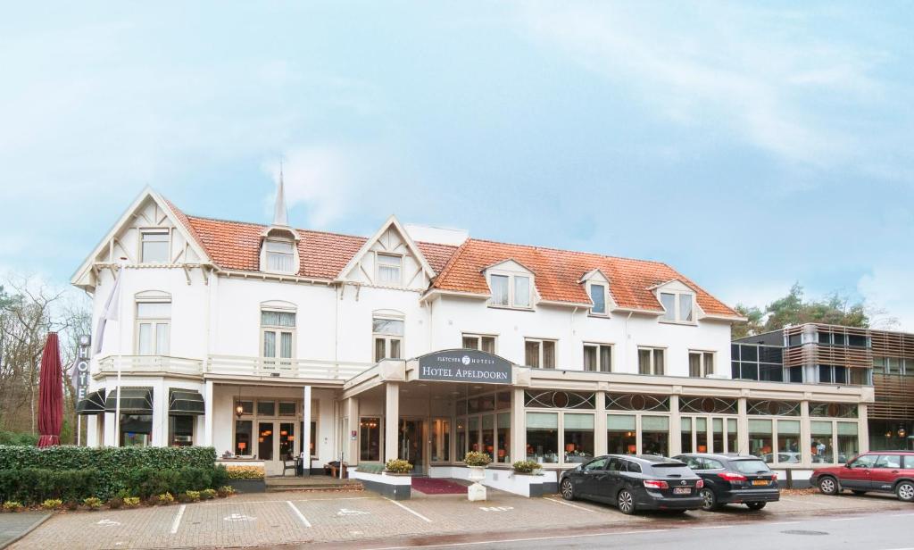 un edificio bianco con macchine parcheggiate di fronte di Fletcher Hotel Apeldoorn ad Apeldoorn