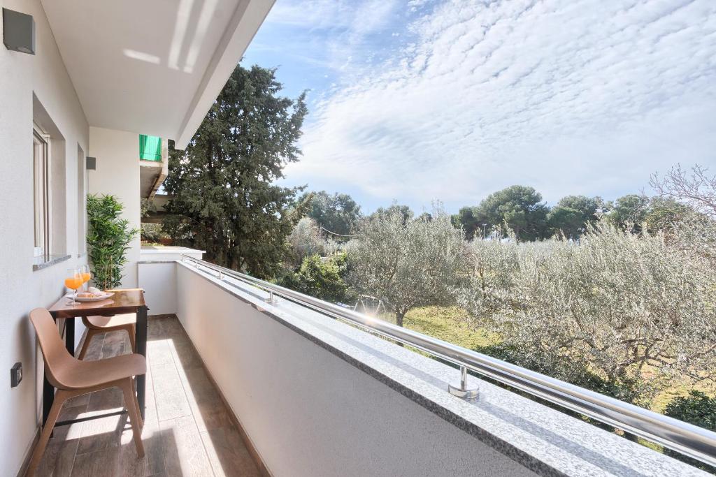 een balkon met een tafel en uitzicht op de bomen bij rose in Fažana