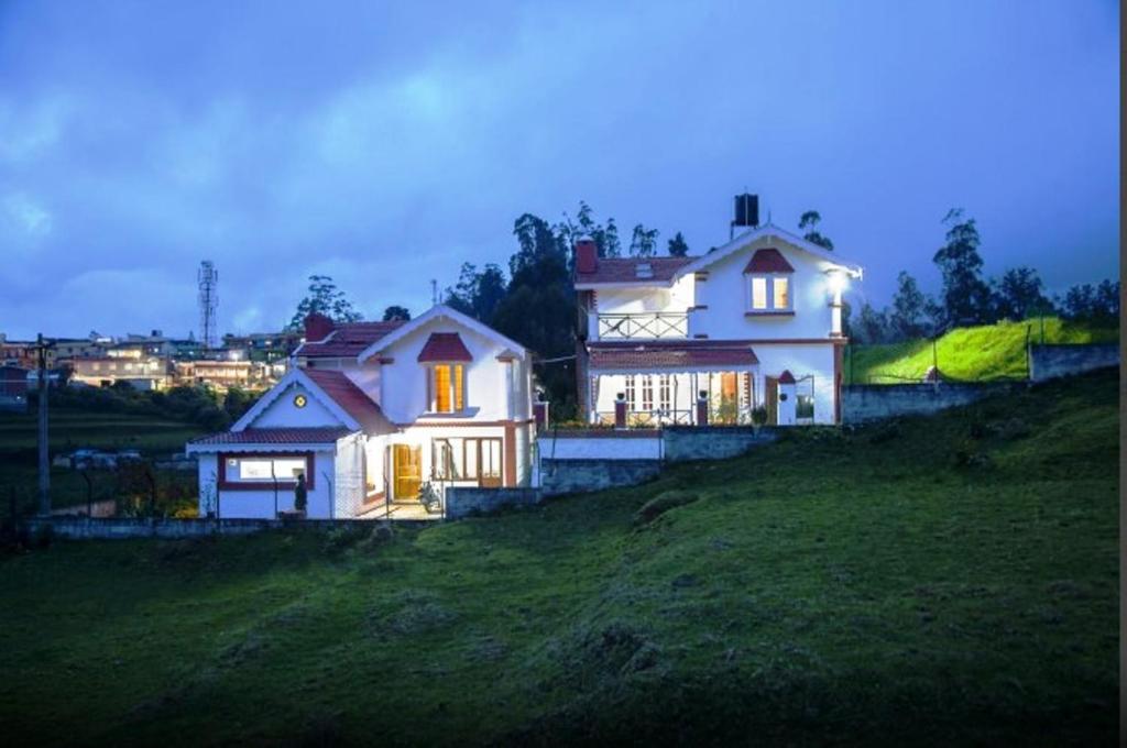 ein weißes Haus auf einem Hügel in der Unterkunft Pine View Stay Ooty in Udagamandalam