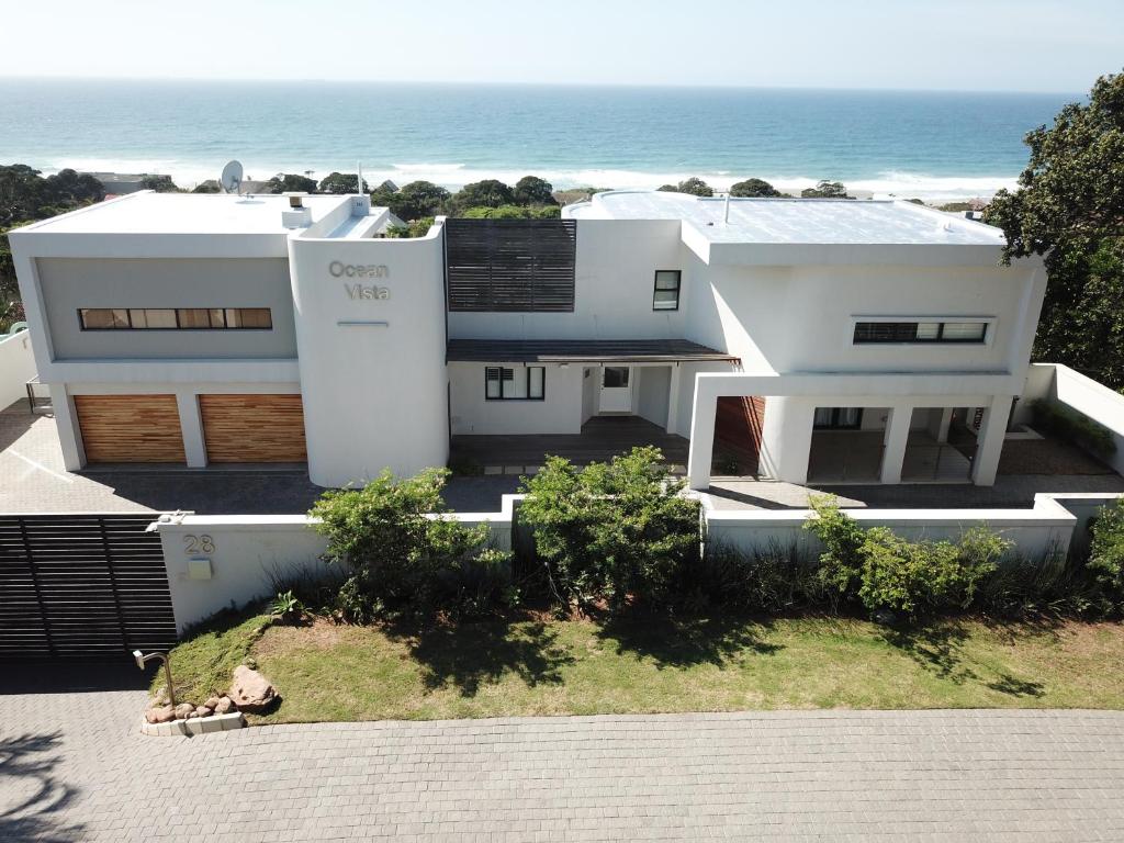 een wit huis met de oceaan op de achtergrond bij Ocean Vista Boutique Guest House in Durban