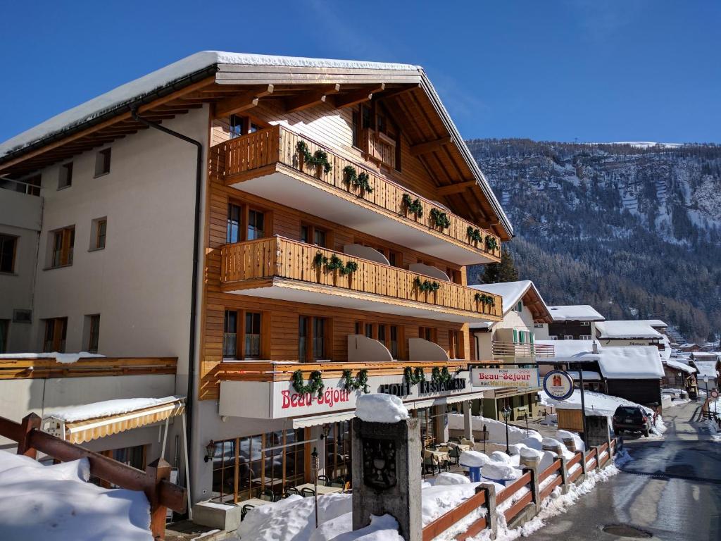 ein großes Gebäude mit Balkon im Schnee in der Unterkunft Hotel Beau-Séjour in Leukerbad