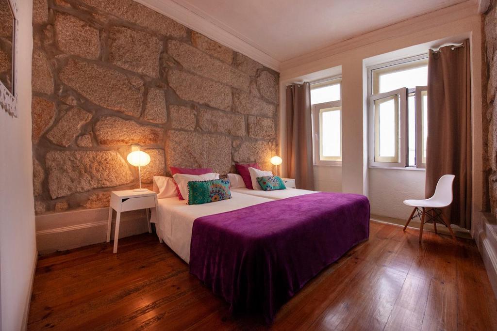 um quarto com uma cama grande e uma parede de pedra em OportoHouse no Porto