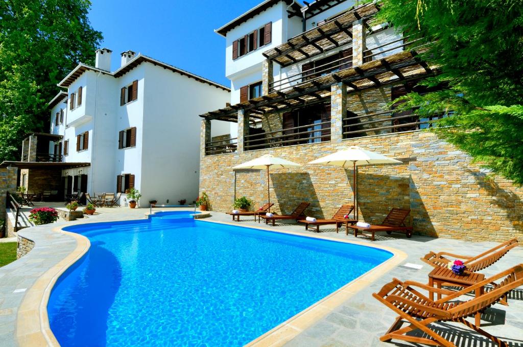 einen Pool mit Stühlen und Sonnenschirmen neben einem Gebäude in der Unterkunft Hotel Zagora in Zagora