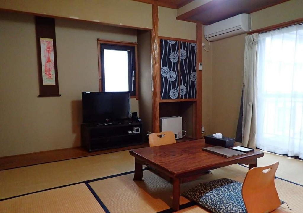 een woonkamer met een tafel en een televisie bij Address Nozawa Japanese Room / Vacation STAY 22751 in Nozawa Onsen