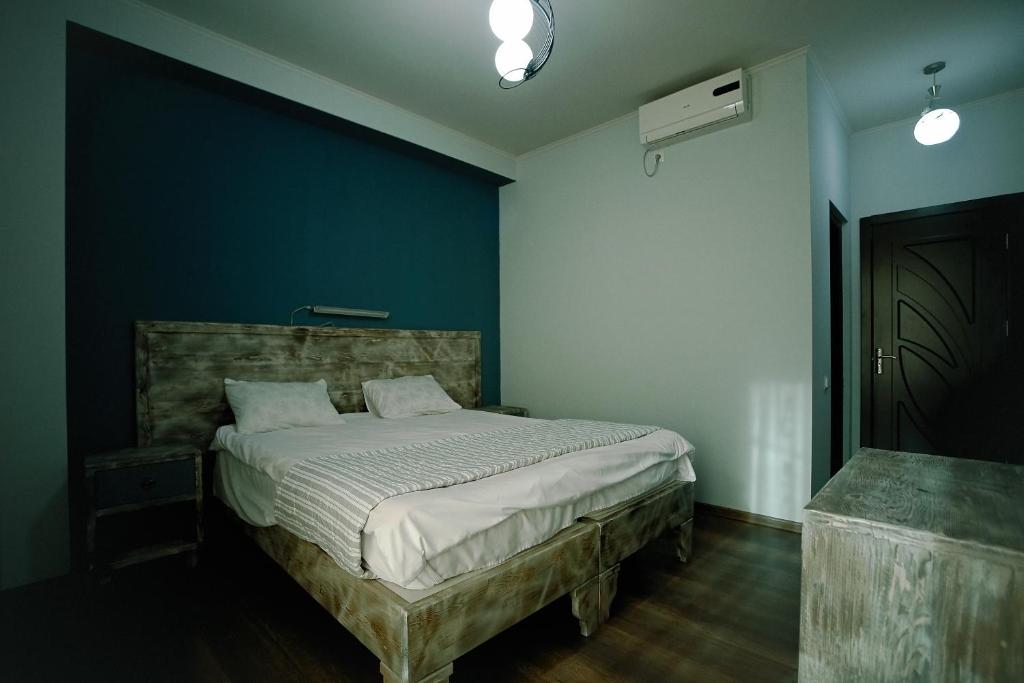 1 dormitorio con 1 cama con pared azul en Hotel Kutaisi Globus, en Kutaisi