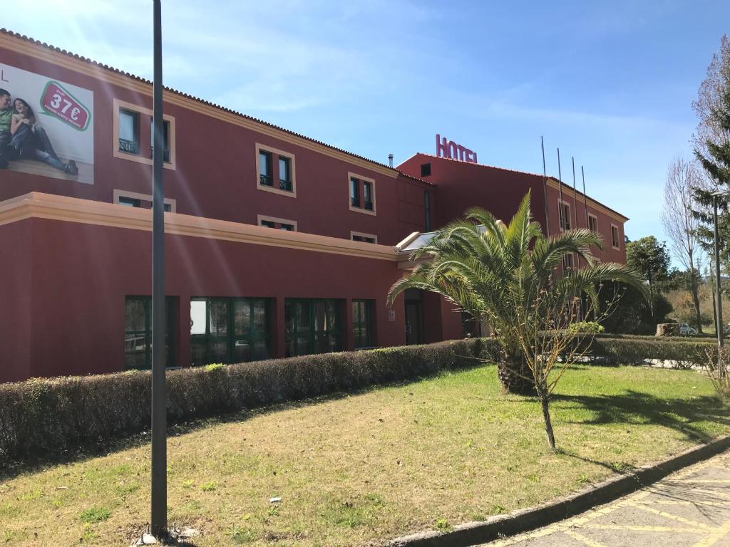 ein rotes Gebäude mit einer Palme davor in der Unterkunft Viseu Garden Hotel in Viseu