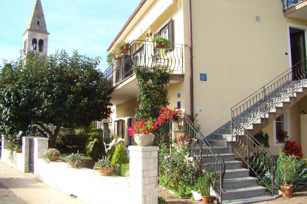 een gebouw met trappen en potplanten en een kerk bij Apartment Complex Orzan Lovrecica in Umag