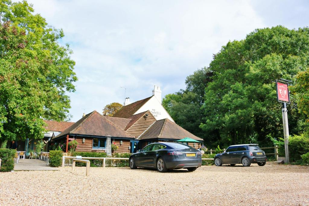 zwei Autos auf einem Parkplatz vor einem Gebäude geparkt in der Unterkunft Cromwell Arms Country Pub with Rooms in Romsey