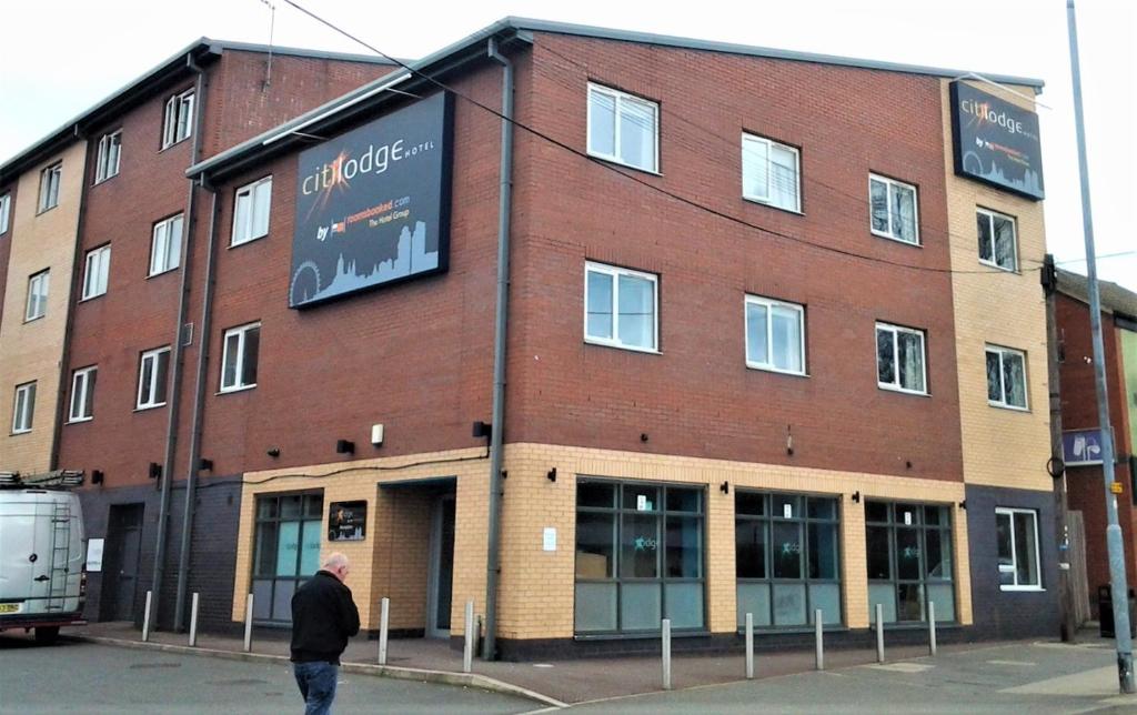 a man walking in front of a brick building at Citilodge Wakefield Hotel by Roomsbooked in Wakefield