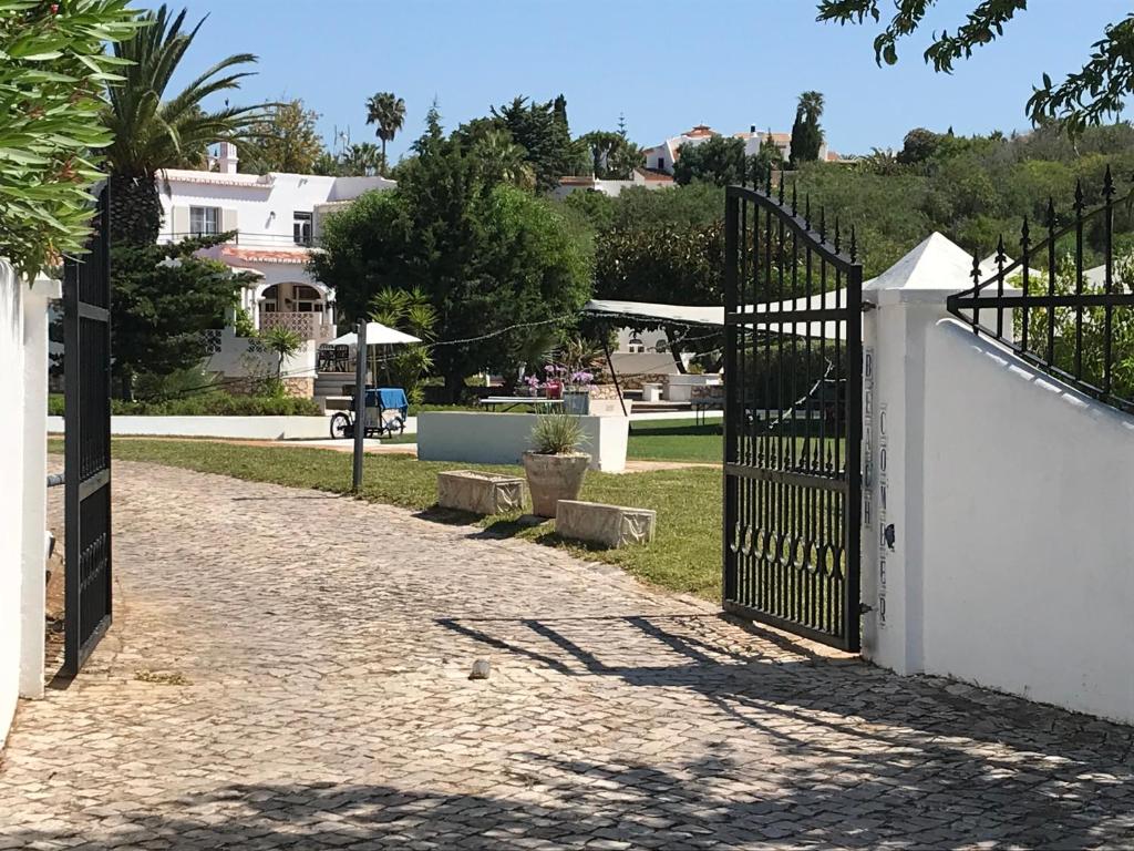 um portão que leva a um parque com árvores e casas em CASA BEACHCOMBER Le jardin des Arts em Lagos