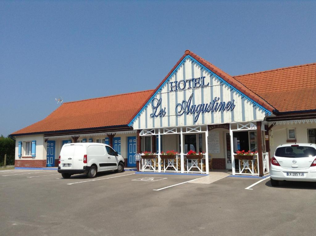 un grand bâtiment avec des voitures garées dans un parking dans l'établissement Les Augustines, à Quend