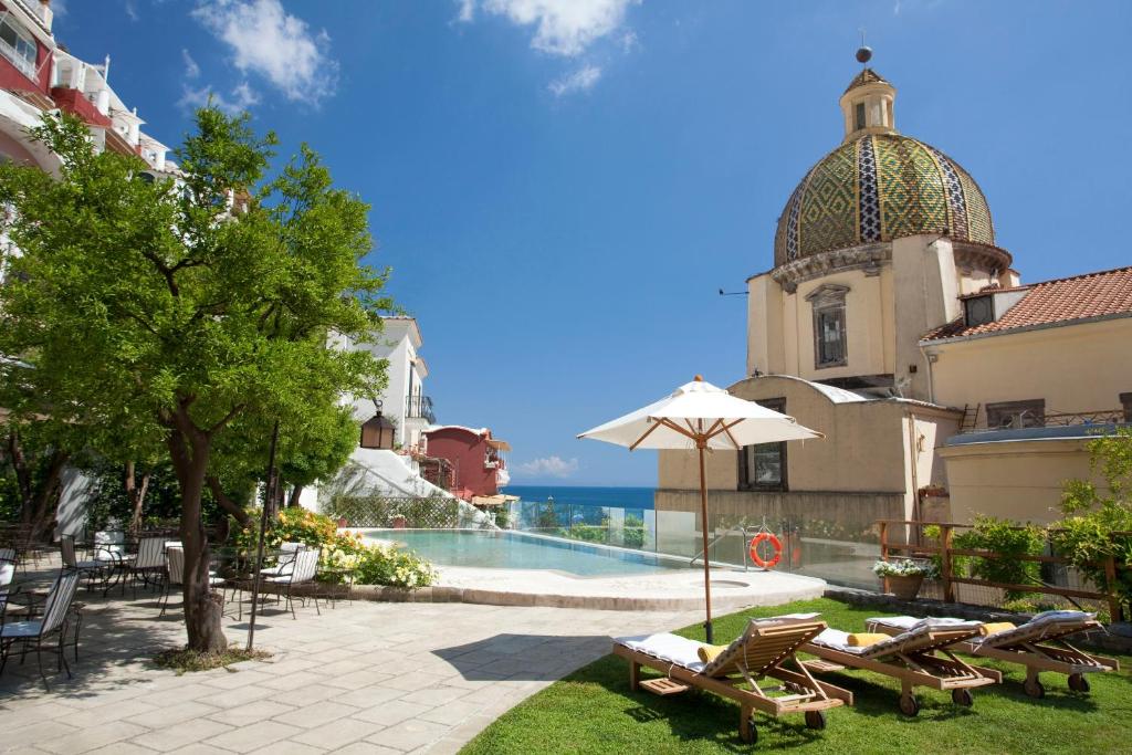 einem Pool mit Stühlen und einem Sonnenschirm neben einem Gebäude in der Unterkunft Hotel Palazzo Murat in Positano