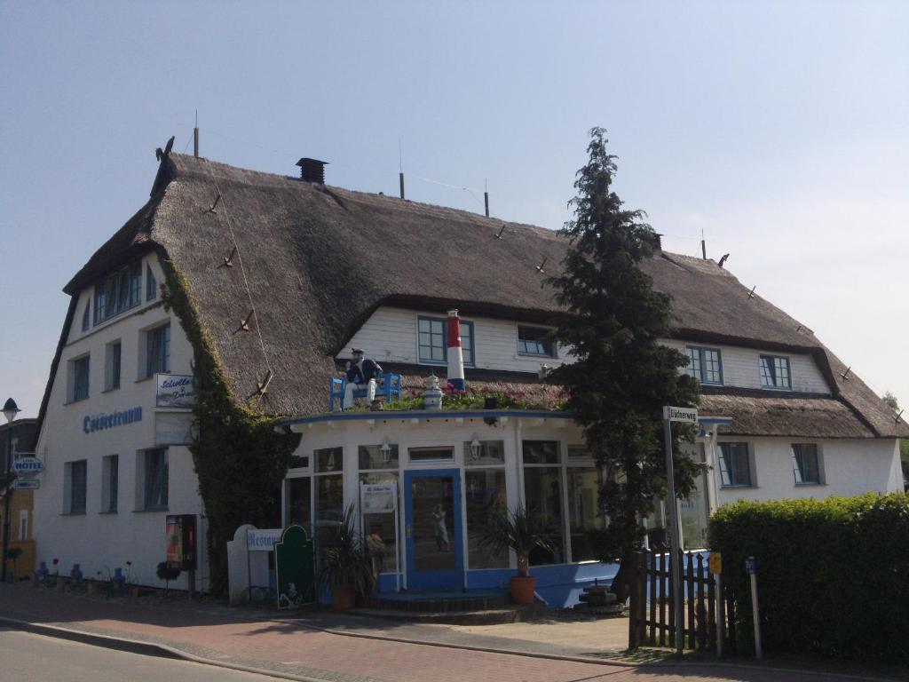 een oud wit gebouw met een rieten dak bij Landhotel Ostseetraum & Fewo in Warnemünde