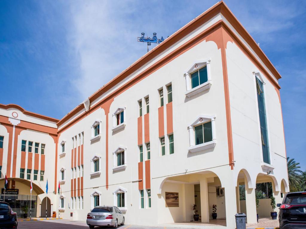 un gran edificio con coches estacionados frente a él en Al Nakheel Hotel Apartments, en Ras al Khaimah