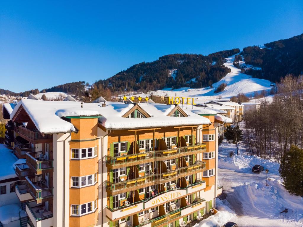 un hotel en las montañas con nieve en el techo en Hotel Sonnschein, en Niederau