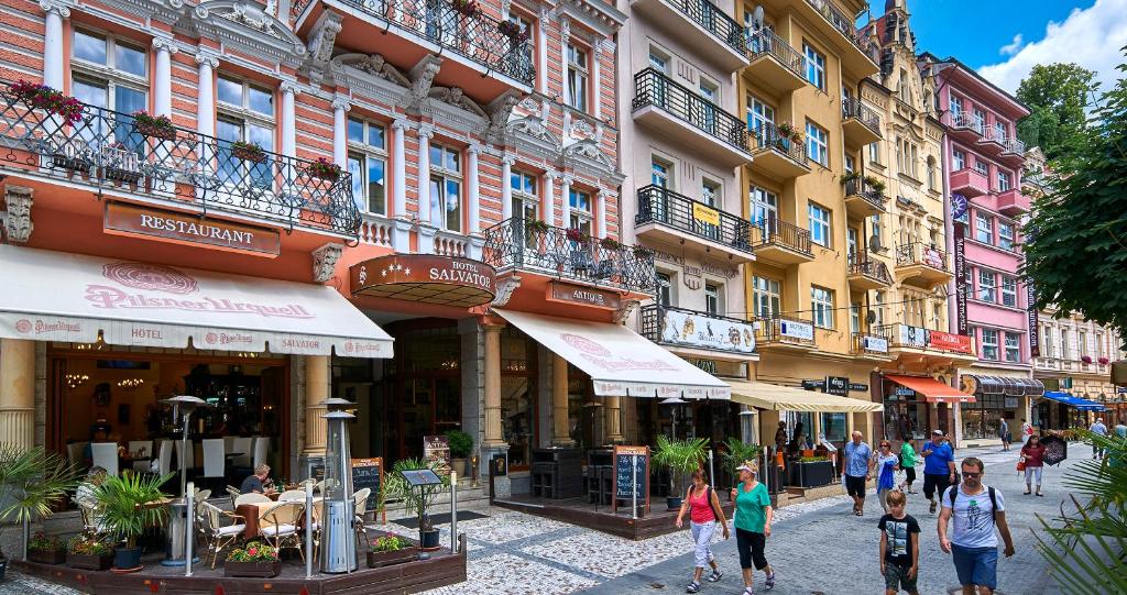 eine Gruppe von Menschen, die eine Straße mit Gebäuden entlang gehen in der Unterkunft Salvator Hotel in Karlsbad