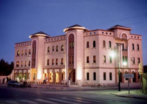 a large white building with a street light in front of it at Résidence El Arich in Tozeur