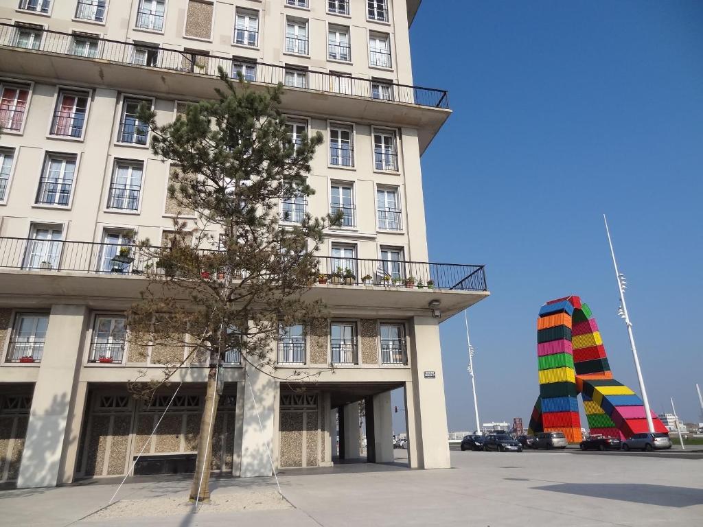 um edifício alto com uma árvore em frente em LE MARITIME em Le Havre