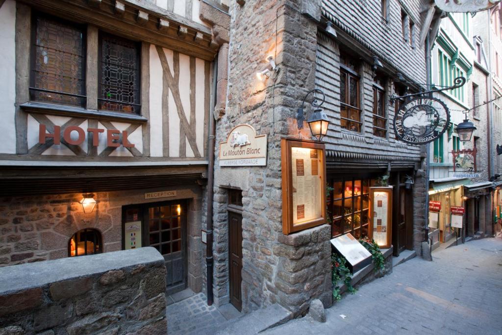 un bâtiment avec une horloge sur le côté d'une rue dans l'établissement Le Mouton Blanc, au Mont-Saint-Michel