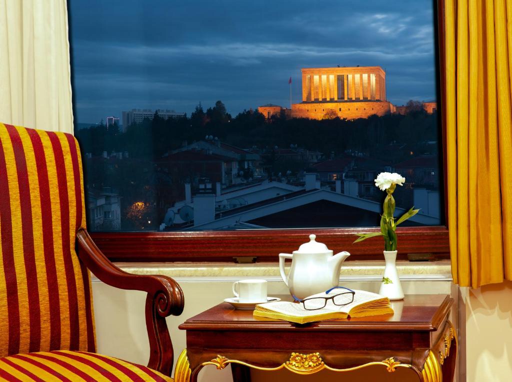 uma mesa com um vaso de flores e copos numa janela em Hotel Ickale em Ancara