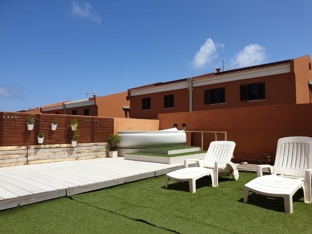 eine Terrasse mit weißen Stühlen und einem Pool auf dem Dach in der Unterkunft La Casa Sahi in Gáldar