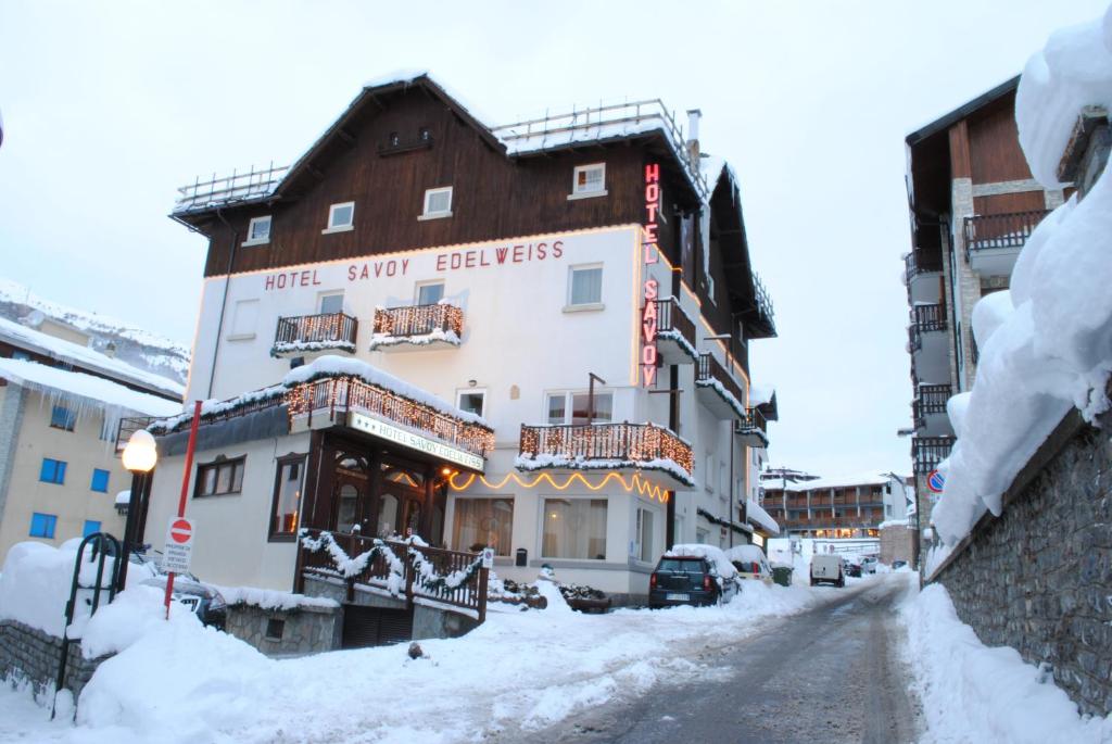 塞斯特雷Hotel Savoy Sestriere的地面上积雪的街道上的建筑