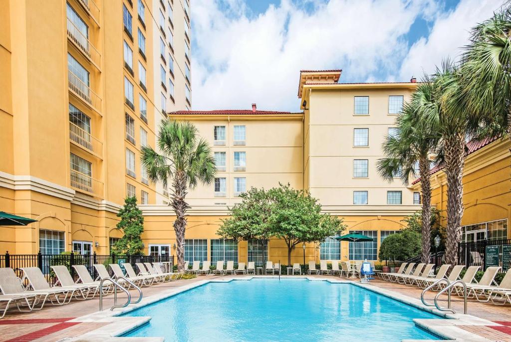 een zwembad voor een gebouw met stoelen en palmbomen bij La Quinta Inn & Suites by Wyndham San Antonio Riverwalk in San Antonio