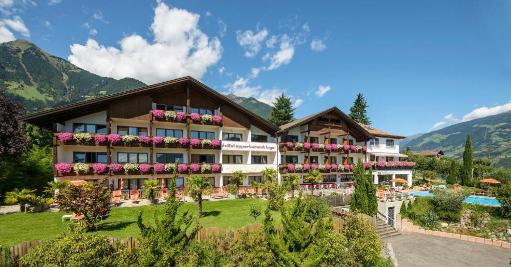 een hotel met een zwembad en bergen op de achtergrond bij Hotel Appartement Inge in Tirolo