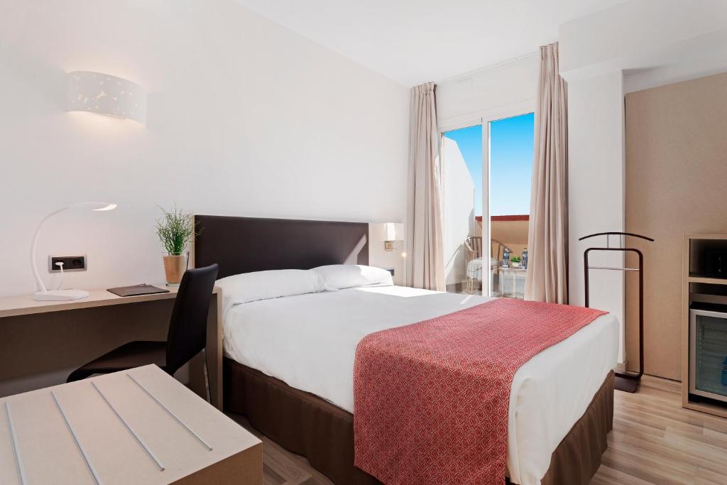 een hotelkamer met een bed, een bureau en een tafel bij Catalonia Hispalis in Sevilla