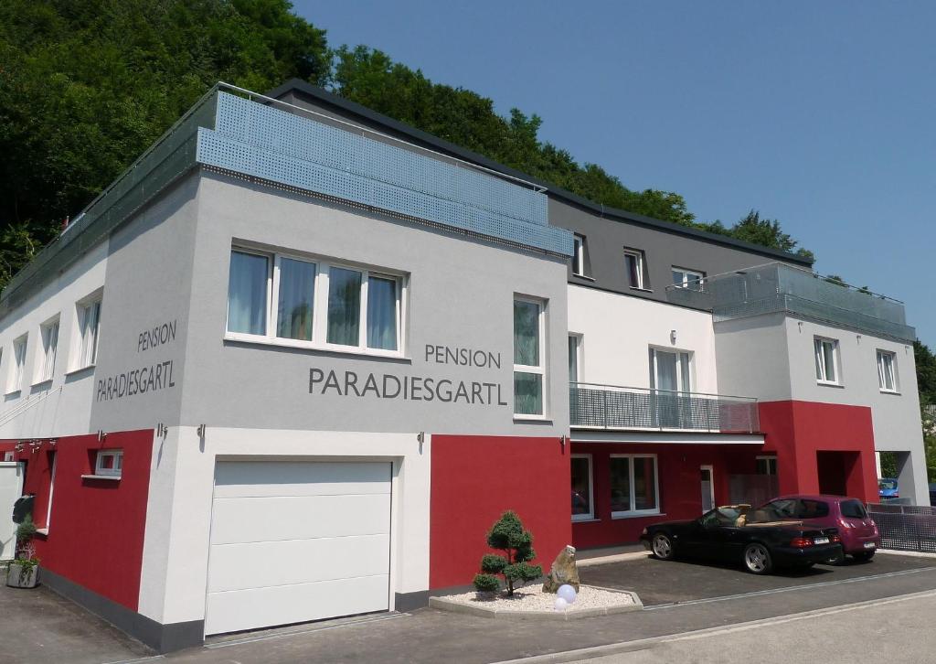 een wit en rood gebouw met een auto voor de deur bij Frühstückspension Paradiesgartl in Amstetten