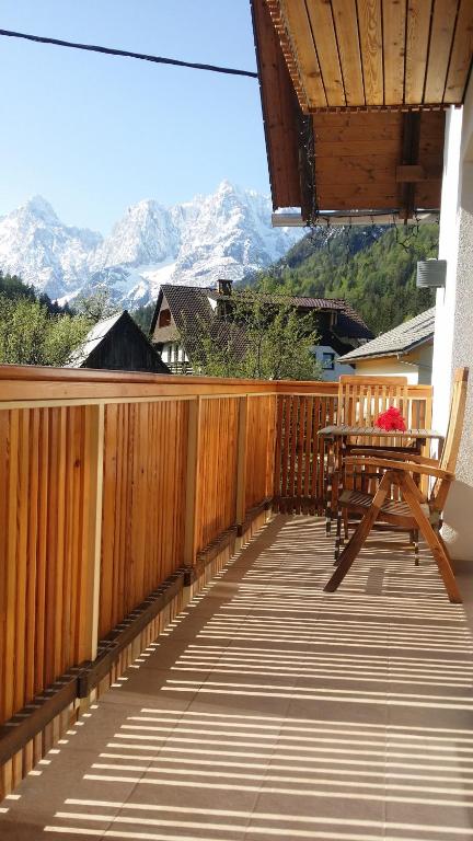 una terraza de madera con mesa, sillas y montañas en Apartments Katja, en Kranjska Gora