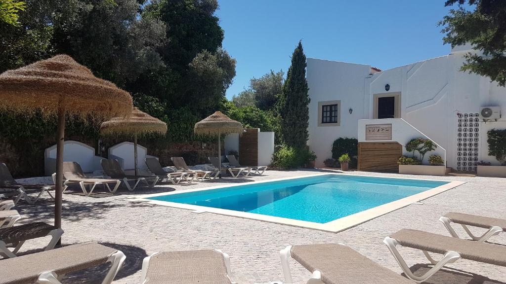 einen Pool mit Stühlen und Sonnenschirmen neben einem Haus in der Unterkunft Casa do Alto in Vilamoura