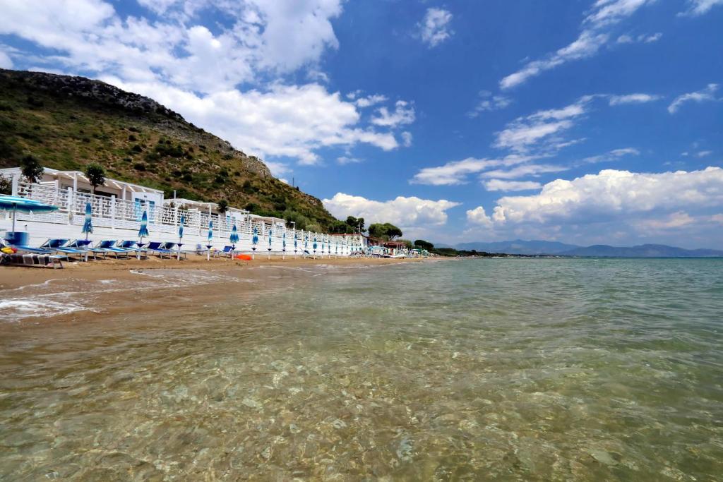 Ein Strand mit einem Haufen weißer Stühle und Wasser in der Unterkunft Le Palme Village in Terracina