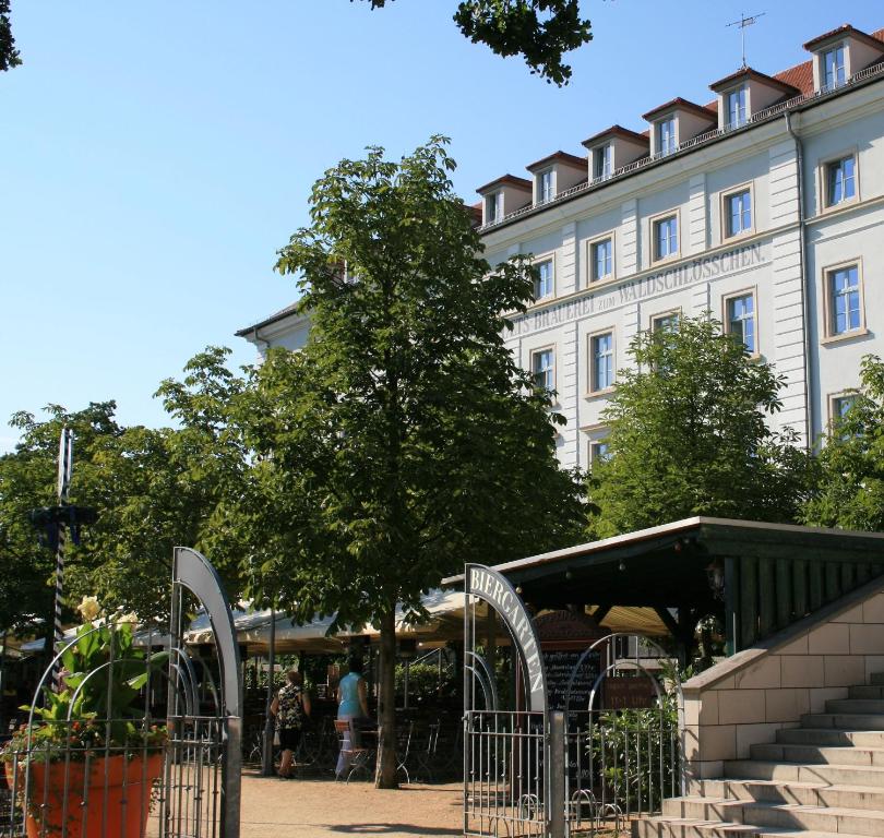 un grand bâtiment blanc avec un arbre en face dans l'établissement Hotel am Waldschlösschen - Brauhaus, à Dresde