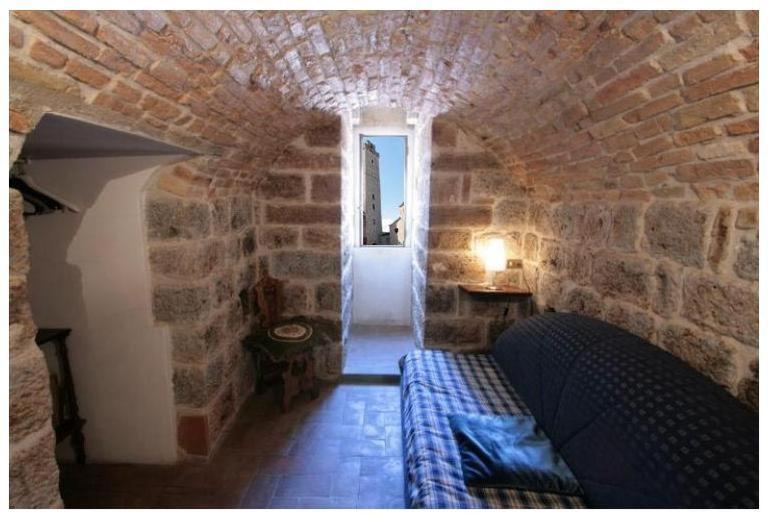 a room with a couch in a stone wall at La Torre Useppi in San Gimignano