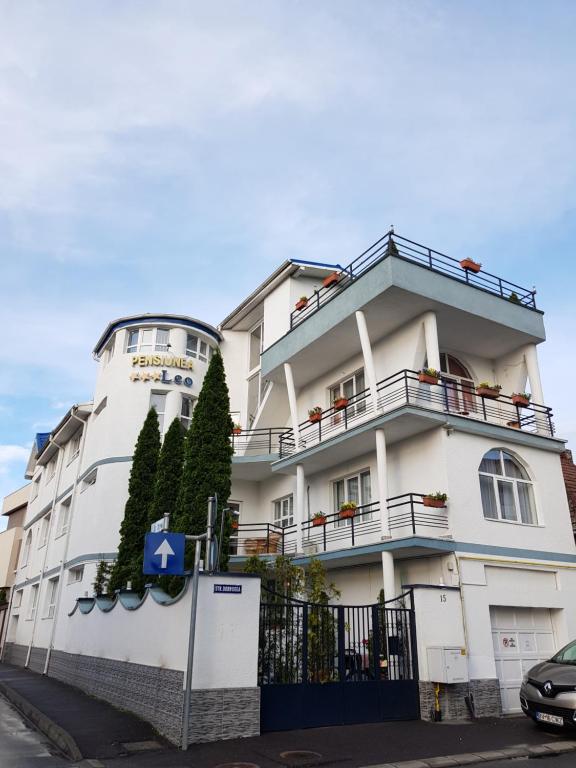 - un bâtiment blanc avec balcon dans une rue dans l'établissement Pensiunea Leo, à Braşov