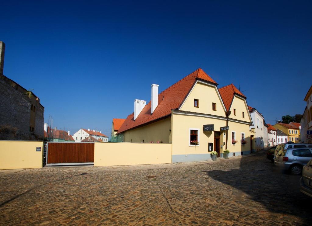 um edifício branco com um telhado vermelho numa rua em Hotel Lahofer em Znojmo