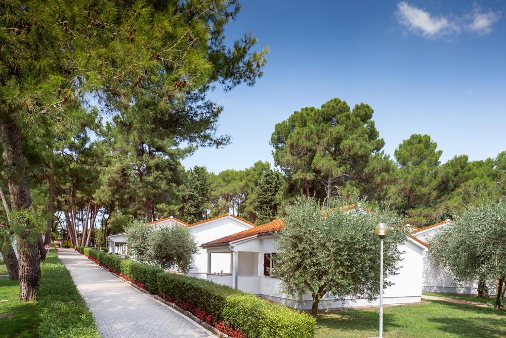 ein weißes Haus mit Bäumen und Bürgersteig in der Unterkunft Apartments Galijot Plava Laguna in Poreč