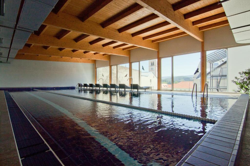 a large swimming pool with chairs in a building at Hotel Kašperk in Kašperské Hory