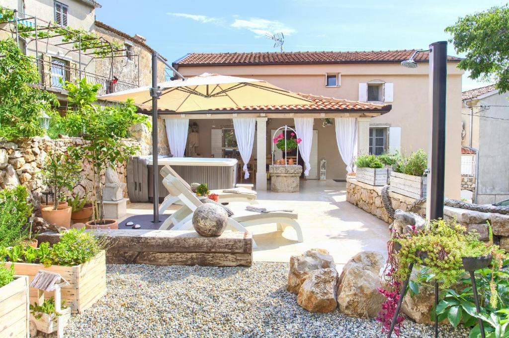 eine Terrasse mit Sonnenschirm und einigen Pflanzen in der Unterkunft White Cottage Heritage House in Čižići