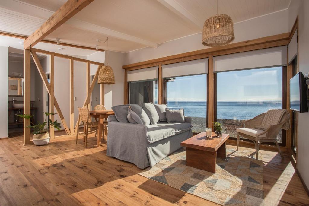 sala de estar con sofá y vistas al océano en Cala Melí, en Puerto Varas