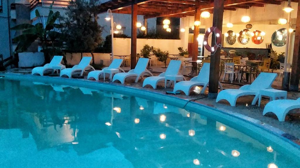 - une piscine avec des chaises blanches et un groupe de personnes dans l'établissement Olives Residence, à Dhërmi